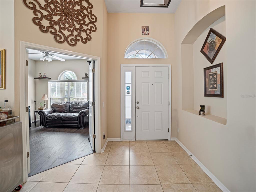 A tiled entryway features a white front door, an arched niche, and a nearby room — 11005 ROCKLEDGE VIEW DRIVE, RIVERVIEW, FL