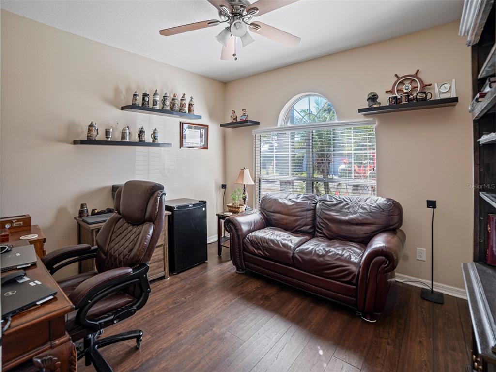 A home office features a leather sofa, a desk with a chair, and wall-mounted shelves — 11005 ROCKLEDGE VIEW DRIVE, RIVERVIEW, FL