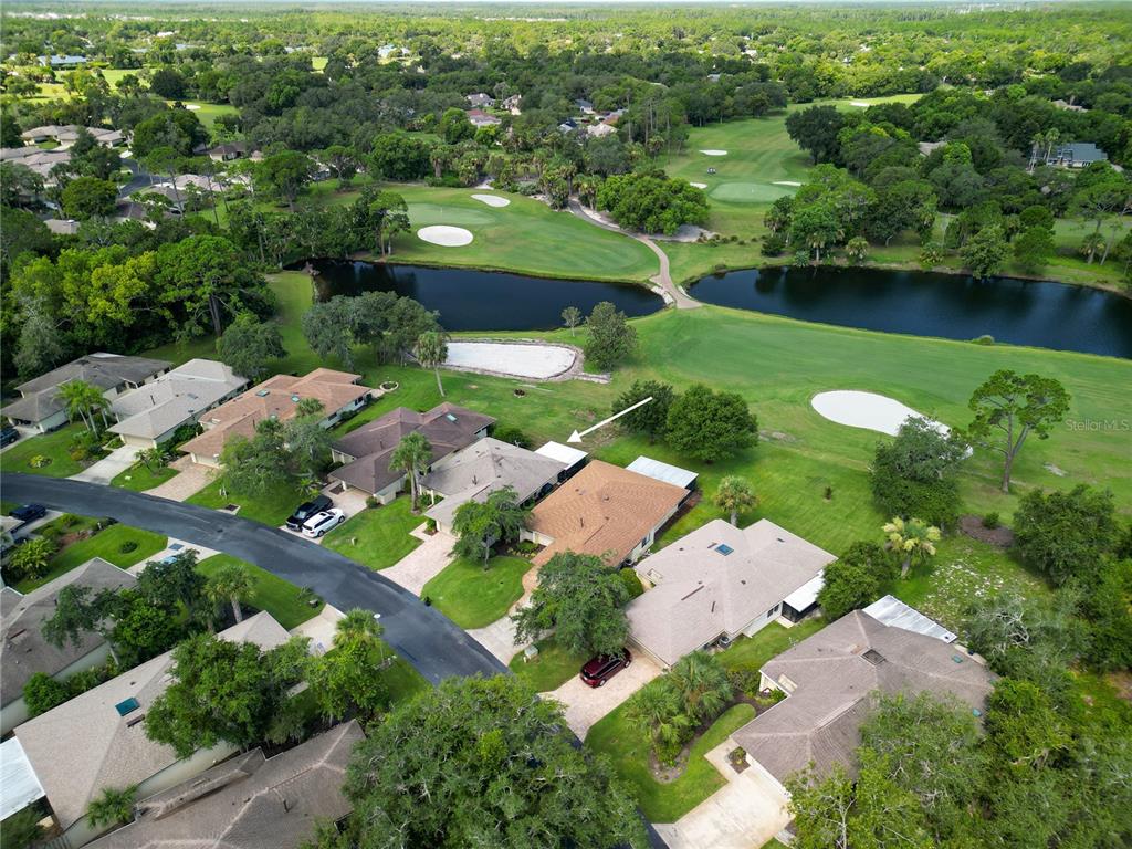 An aerial view shows a residential neighborhood with houses bordering a golf course and lake — 218 CANTERBURY CIRCLE, NEW SMYRNA BEACH, FL