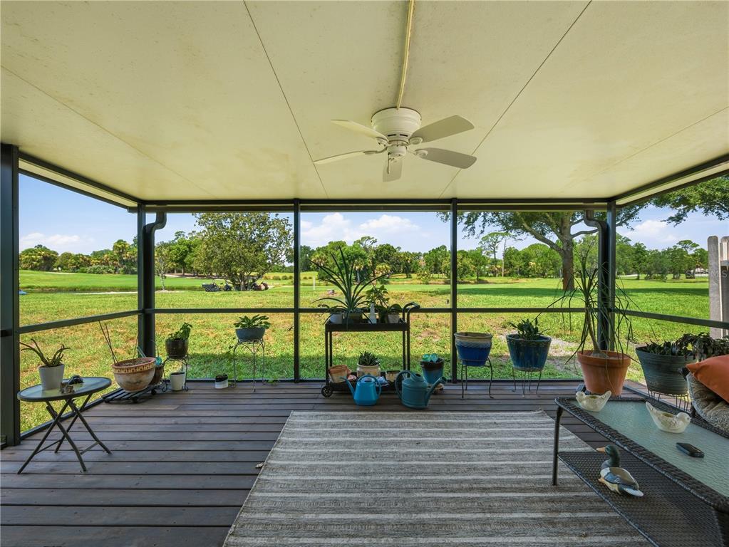 A screened-in porch with a ceiling fan, wood decking, and a view of a golf course — 218 CANTERBURY CIRCLE, NEW SMYRNA BEACH, FL