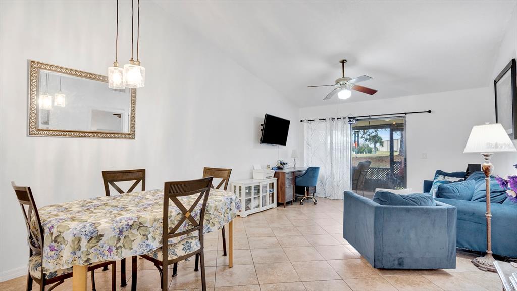 An open-concept living and dining area with tile floors, a ceiling fan, and sliding doors — 12 PINE ISLAND CIRCLE, KISSIMMEE, FL