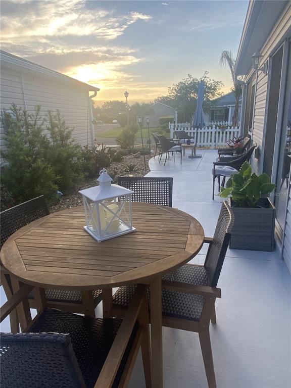 A patio features a round wooden table with chairs and a white lantern at sunset — 1648 ABASCO COURT, THE VILLAGES, FL