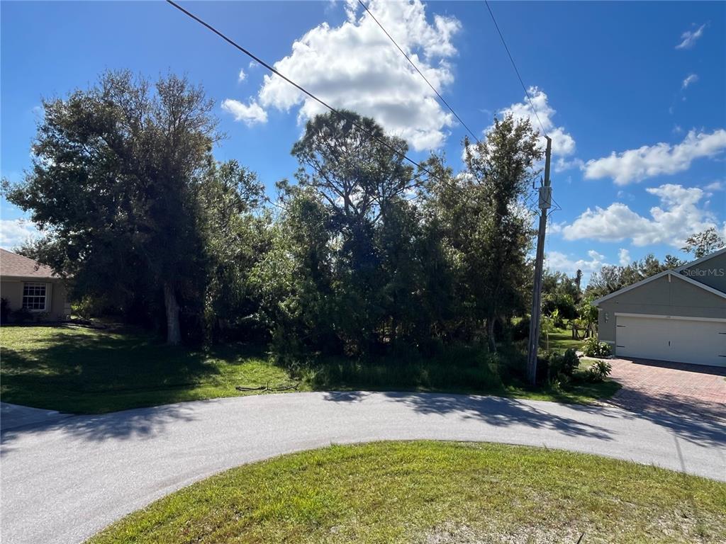 A vacant, wooded residential lot is situated between two houses along a curved street — 304 OYAHUE STREET, PUNTA GORDA, FL