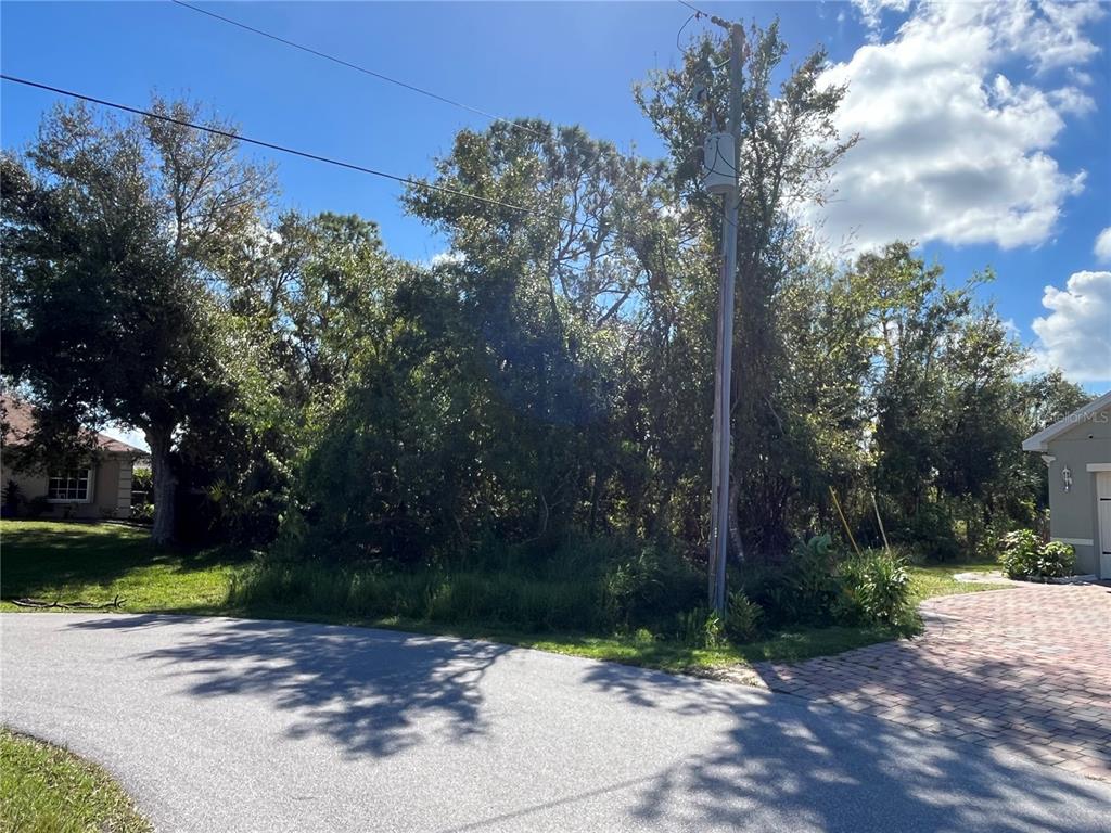 A wooded vacant lot sits between two houses along a paved residential street — 304 OYAHUE STREET, PUNTA GORDA, FL