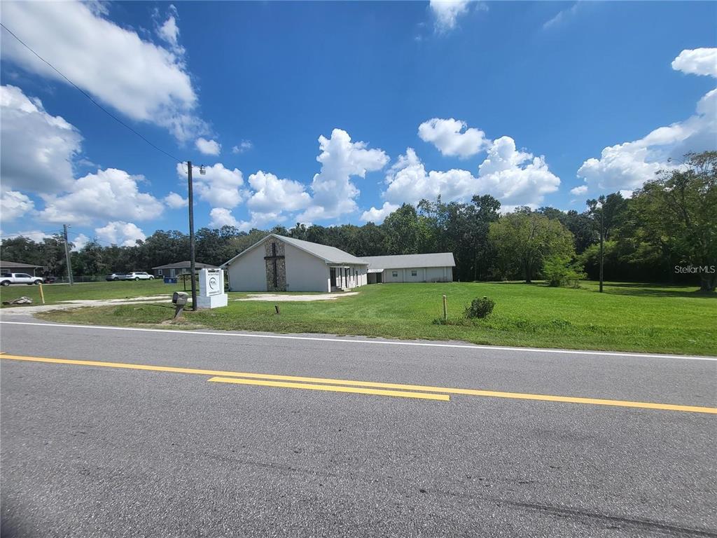 A light-colored church building with a stone cross sits beside a road under blue skies — 4626 S PIPKIN ROAD, LAKELAND, FL