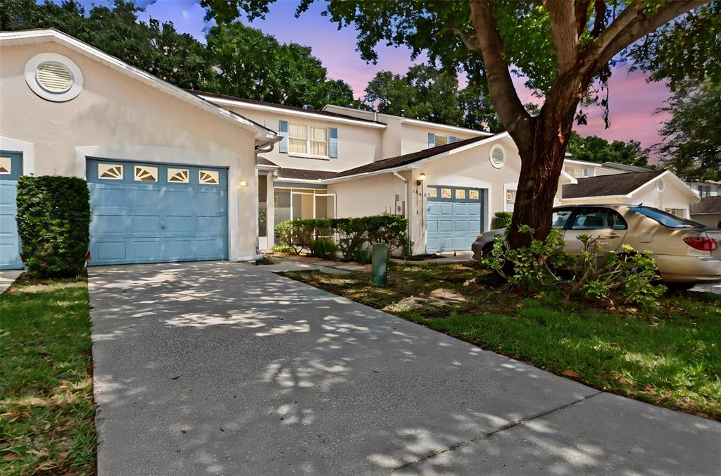 A two-story townhouse exterior with light-colored stucco, blue garage doors, and a concrete driveway — 2330 SE ROYAL ISLE, WINTER HAVEN, FL
