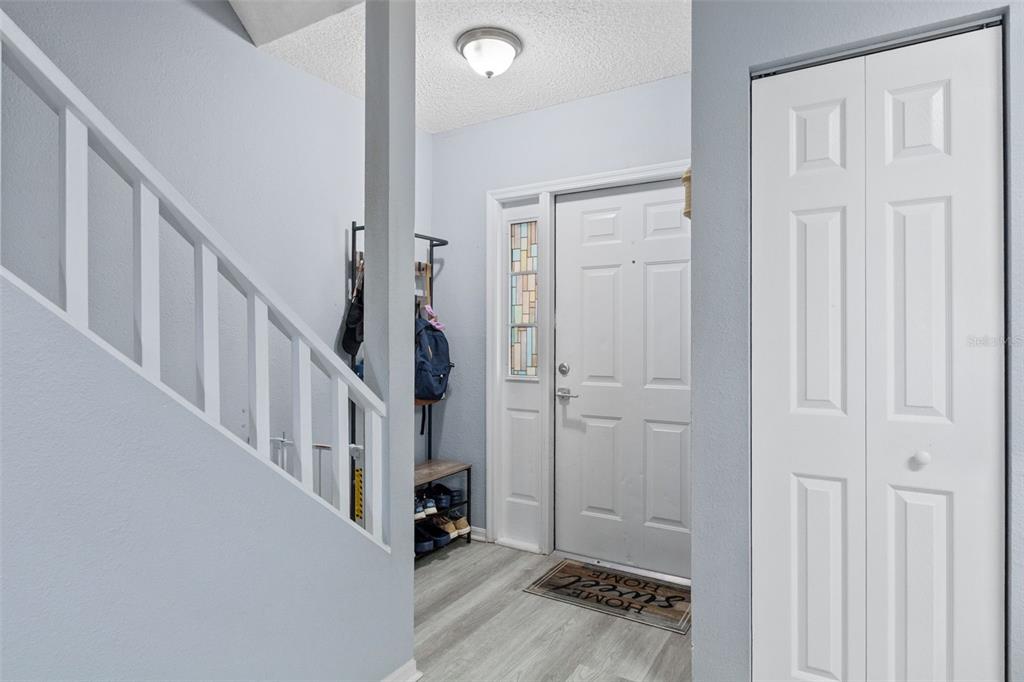 A foyer features light wood-look flooring, a white staircase railing, and a white front door — 2330 SE ROYAL ISLE, WINTER HAVEN, FL