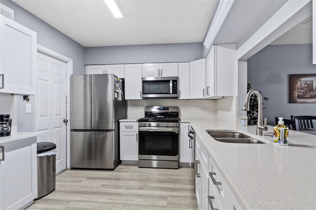 A kitchen with white cabinets, stainless steel appliances, and light-colored countertops — 2330 SE ROYAL ISLE, WINTER HAVEN, FL