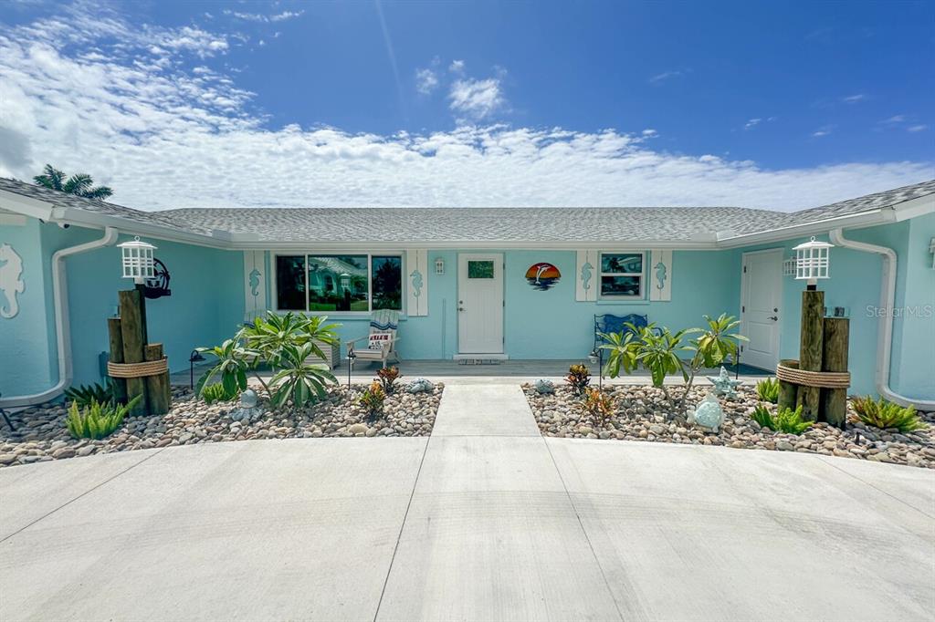 A light blue, single-story house features a concrete driveway, rock landscaping, and a white door — 1945 MICHIGAN AVENUE, ENGLEWOOD, FL