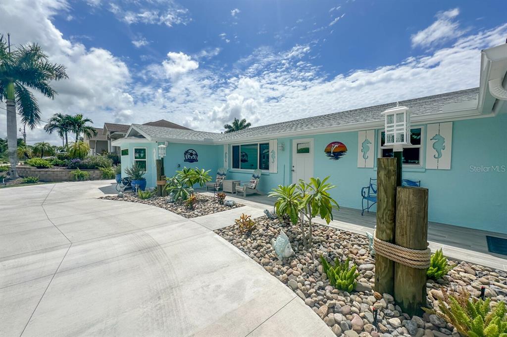 A light blue exterior house features a concrete driveway, rock landscaping, and nautical-themed decor — 1945 MICHIGAN AVENUE, ENGLEWOOD, FL