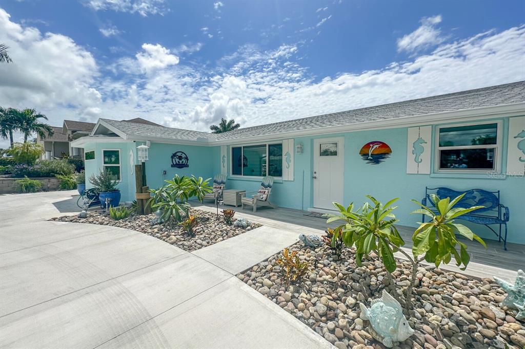A light blue house exterior features a concrete driveway, rock landscaping, and a front porch — 1945 MICHIGAN AVENUE, ENGLEWOOD, FL