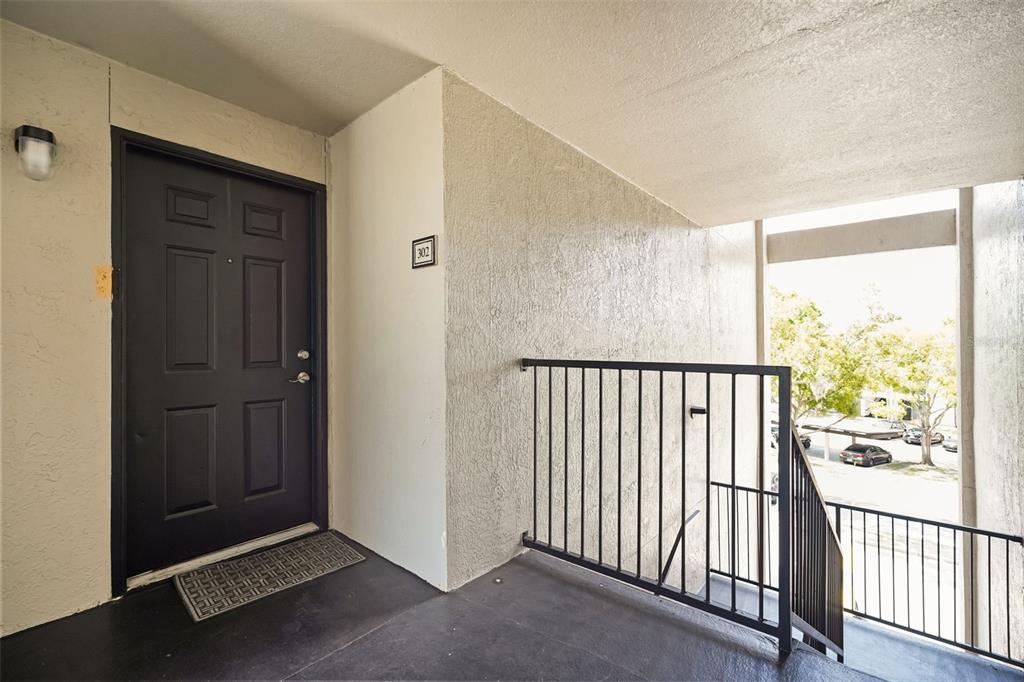 A dark front door with a number 302 sign sits on an outdoor apartment balcony — 7511 SEURAT STREET UNIT 10302, ORLANDO, FL