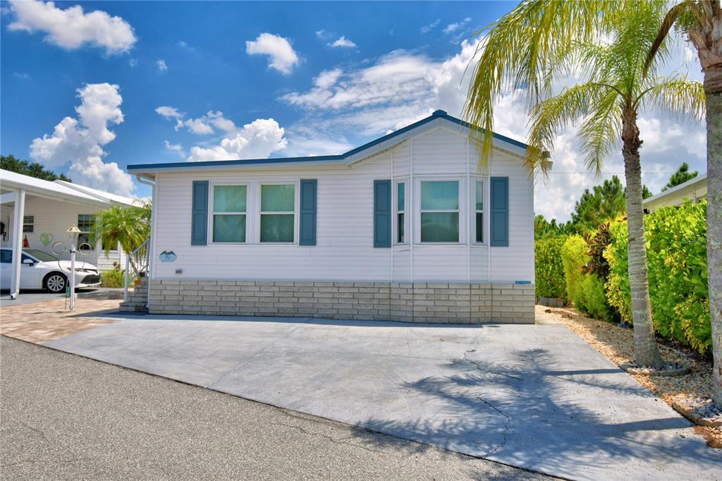 A white mobile home with blue shutters and a concrete driveway under a blue sky — 251 PATTERSON ROAD UNIT I47, HAINES CITY, FL