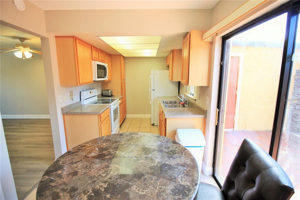 A kitchen with light wood cabinets, laminate countertops, and a round marble-topped dining table — 7446 WYNNEWOOD SQUARE UNIT 190, WINTER PARK, FL