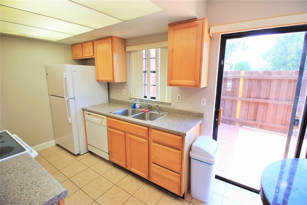 A kitchen with light wood cabinets, a white refrigerator, a double sink, and tile flooring — 7446 WYNNEWOOD SQUARE UNIT 190, WINTER PARK, FL