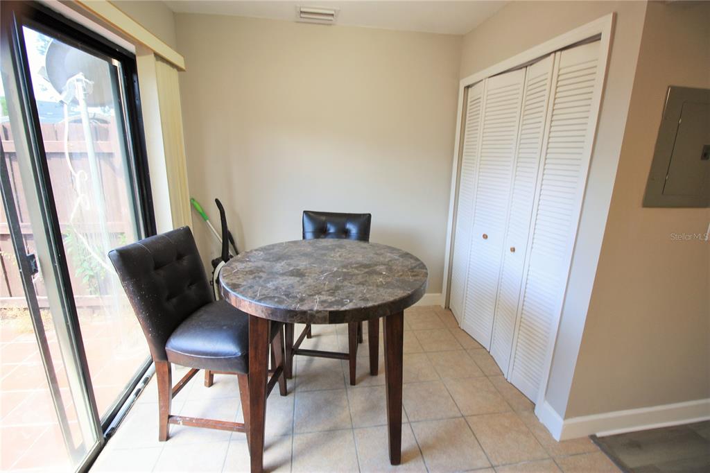 A dining area features a round marble-top table, two dark chairs, tile flooring, and sliding doors — 7446 WYNNEWOOD SQUARE UNIT 190, WINTER PARK, FL