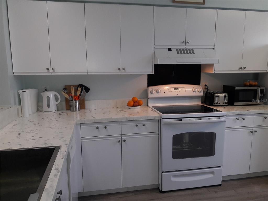 A kitchen features white cabinets, a white stove, and light-colored marble-patterned countertops — 2713 60TH AVENUE DRIVE W, BRADENTON, FL