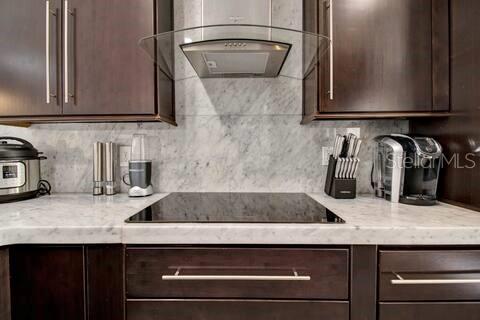 A kitchen features dark wood cabinets, a marble backsplash, and a glass-topped stove — 191 CLUB VILLAS LANE, KISSIMMEE, FL