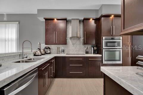 A kitchen features dark wood cabinets, stainless steel appliances, and white marble countertops — 191 CLUB VILLAS LANE, KISSIMMEE, FL