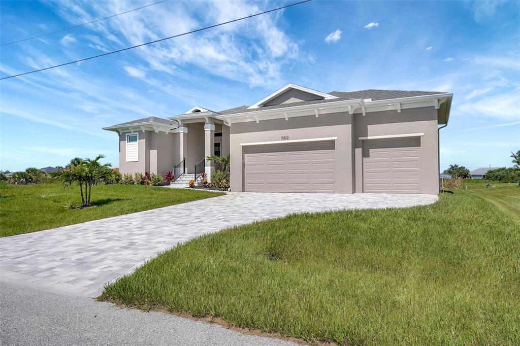 A single-story house with a beige stucco exterior, a three-car garage, and a paved driveway — 10812 MCALESTER CIRCLE, PORT CHARLOTTE, FL