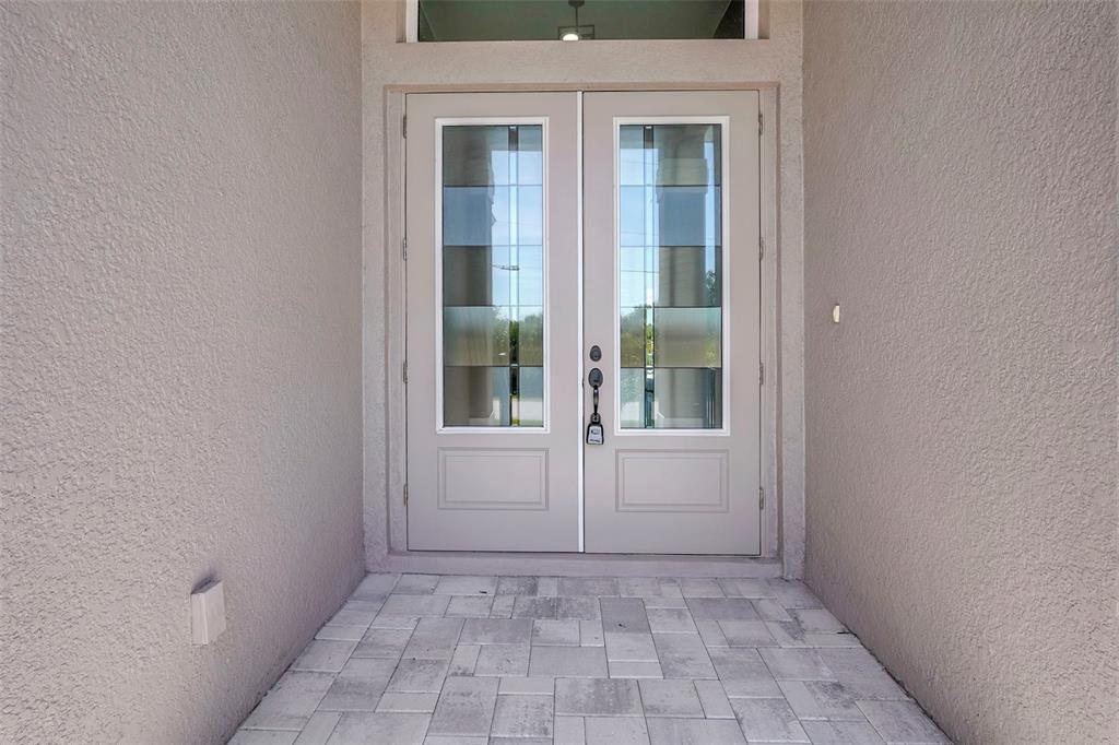 A beige double front door with glass panels sits at the entrance of a paved porch — 10812 MCALESTER CIRCLE, PORT CHARLOTTE, FL
