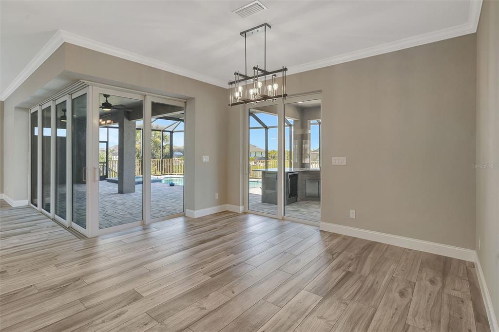 A dining room with wood-look tile flooring, a modern chandelier, and sliding glass doors — 10812 MCALESTER CIRCLE, PORT CHARLOTTE, FL