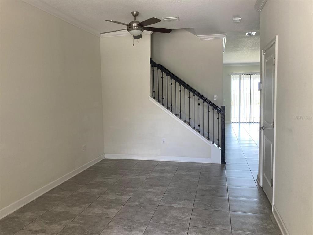 A room with gray tile flooring, a ceiling fan, and a staircase with black railings — 1348 ROYAL ST GEORGE BOULEVARD, DAVENPORT, FL