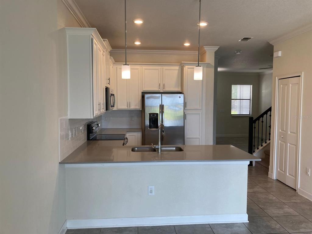 A kitchen with white cabinets, stainless steel appliances, and a peninsula countertop — 1348 ROYAL ST GEORGE BOULEVARD, DAVENPORT, FL