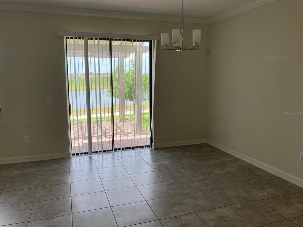 A dining area with tile flooring, a chandelier, and sliding glass doors overlooking a lake — 1348 ROYAL ST GEORGE BOULEVARD, DAVENPORT, FL