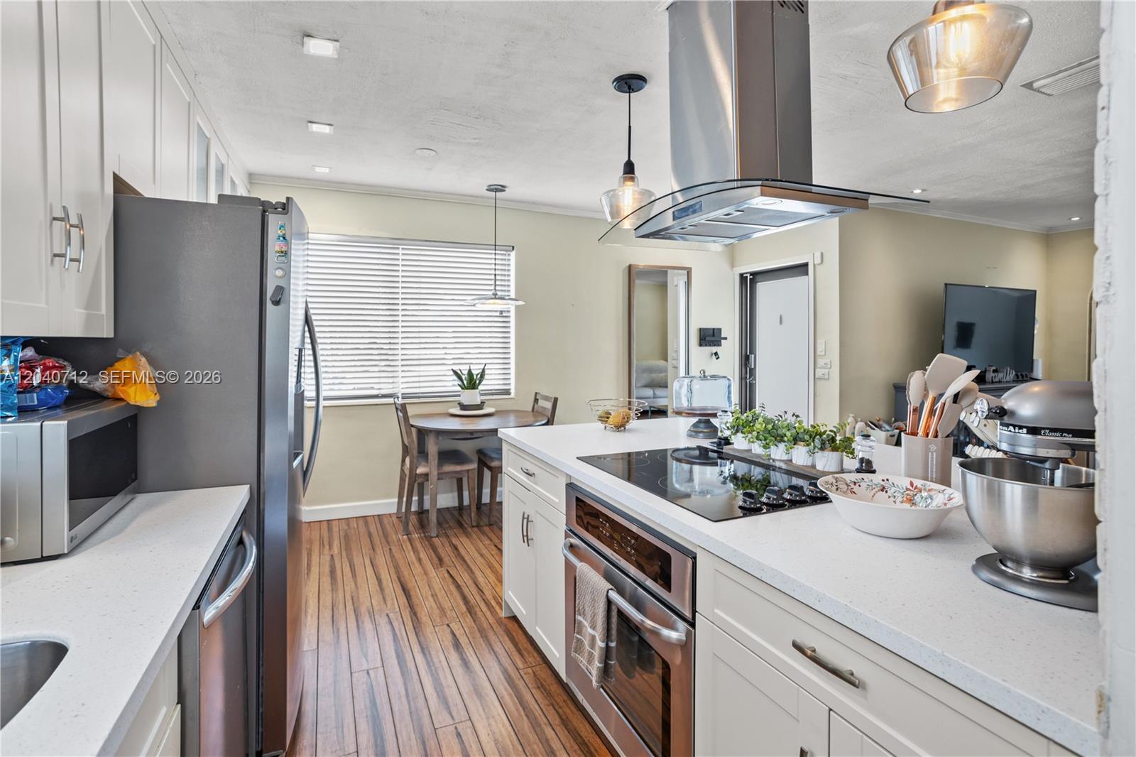 A kitchen features white cabinets, stainless steel appliances, a center island, and wood-look flooring — 19310 Christmas Rd, Cutler Bay FL 33157, CUTLER BAY, FL