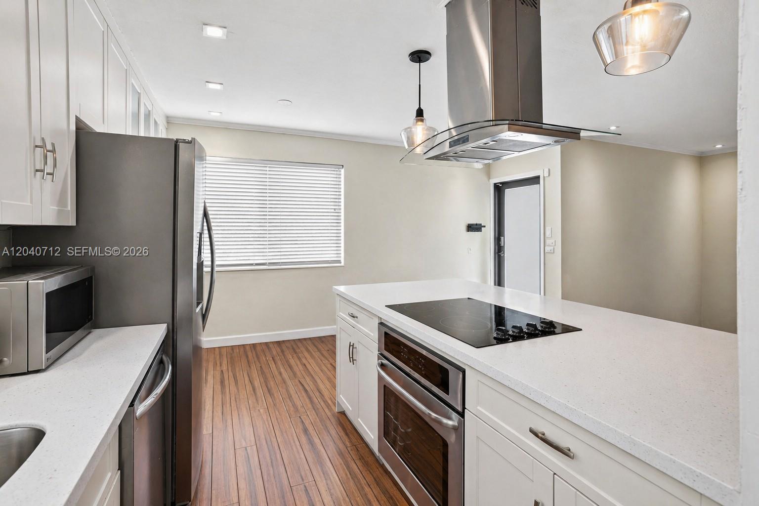 A modern kitchen features white cabinets, stainless steel appliances, and a central island with cooktop — 19310 Christmas Rd, Cutler Bay FL 33157, CUTLER BAY, FL