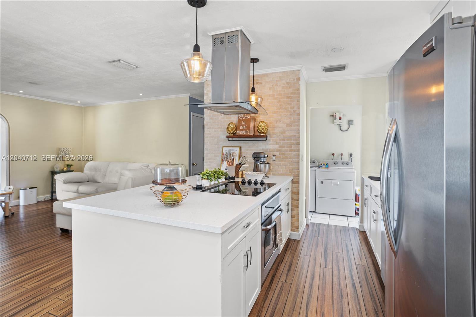 A kitchen features a white island with a cooktop, stainless appliances, and a brick backsplash — 19310 Christmas Rd, Cutler Bay FL 33157, CUTLER BAY, FL