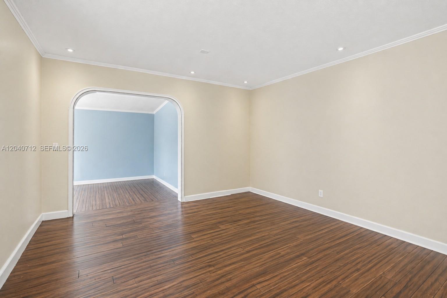 An empty room with beige walls, dark wood flooring, and an arched doorway — 19310 Christmas Rd, Cutler Bay FL 33157, CUTLER BAY, FL