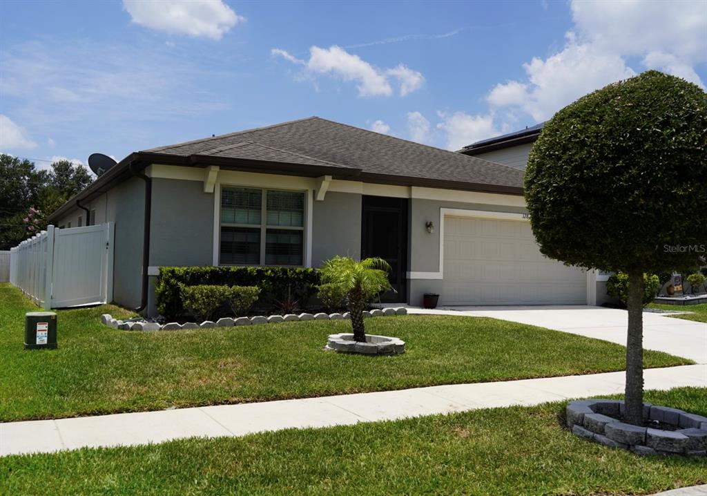 A single-story gray house with a two-car garage and a manicured front lawn — 128 CITRUS ISLE STREET S, DAVENPORT, FL