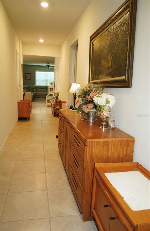 A hallway features tile flooring, a wooden dresser with floral arrangements, and a framed painting — 128 CITRUS ISLE STREET S, DAVENPORT, FL