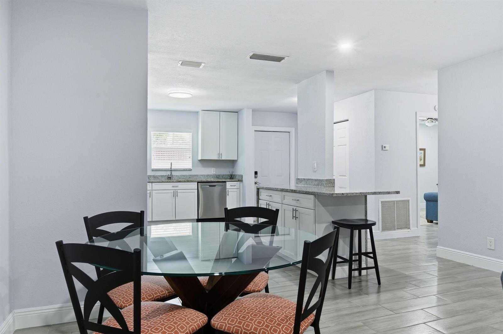 A dining area with a glass table and chairs sits in front of a white kitchen — 586 Laconia Circle, Lake Worth FL 33467, LAKE WORTH, FL