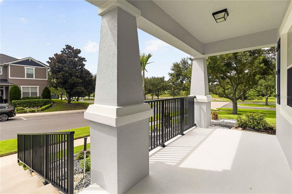 A covered porch features concrete flooring, black metal railings, and two large stucco columns — 2071 RAFTON ROAD, APOPKA, FL