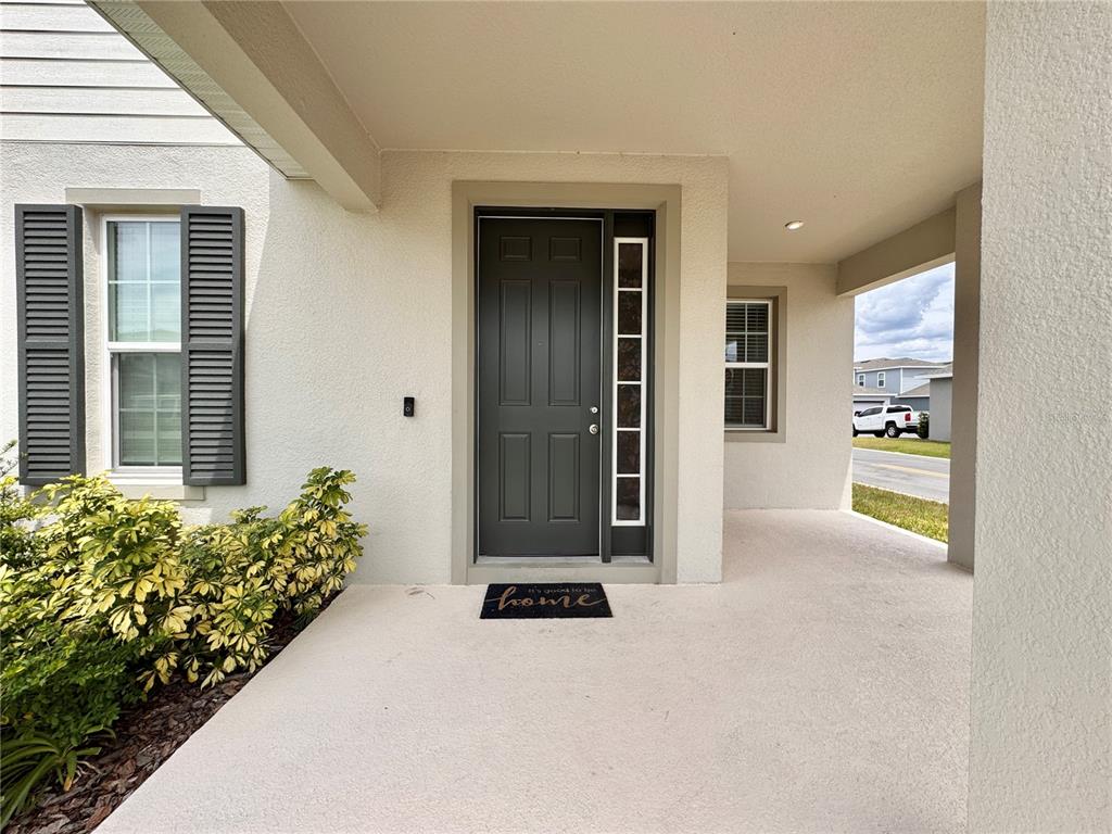 A covered front porch features a dark gray door with a side window and shutters — 3954 GREAT SMOKEY WAY, APOPKA, FL