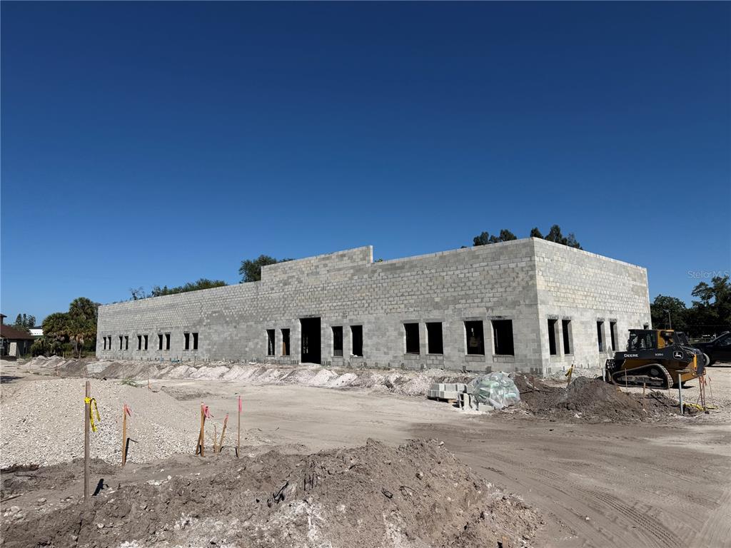 A partially constructed concrete block building stands on a dirt lot under a clear sky — 6204 INTERBAY BOULEVARD, TAMPA, FL