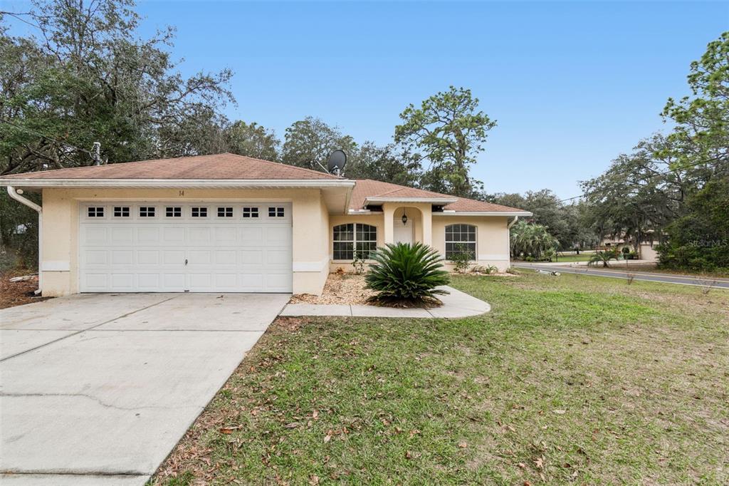A single-story house with a beige stucco exterior, a two-car garage, and a concrete driveway — 14 S CHARLES AVENUE, INVERNESS, FL