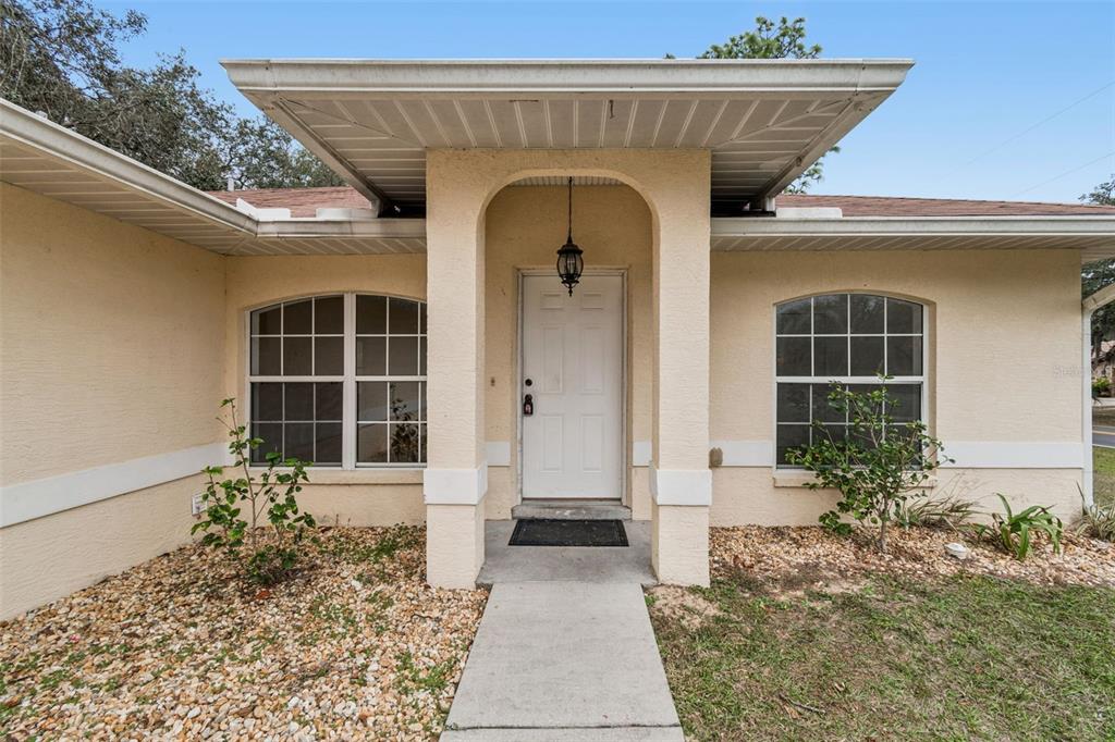 The exterior of a beige house features a covered entryway with an arched porch — 14 S CHARLES AVENUE, INVERNESS, FL