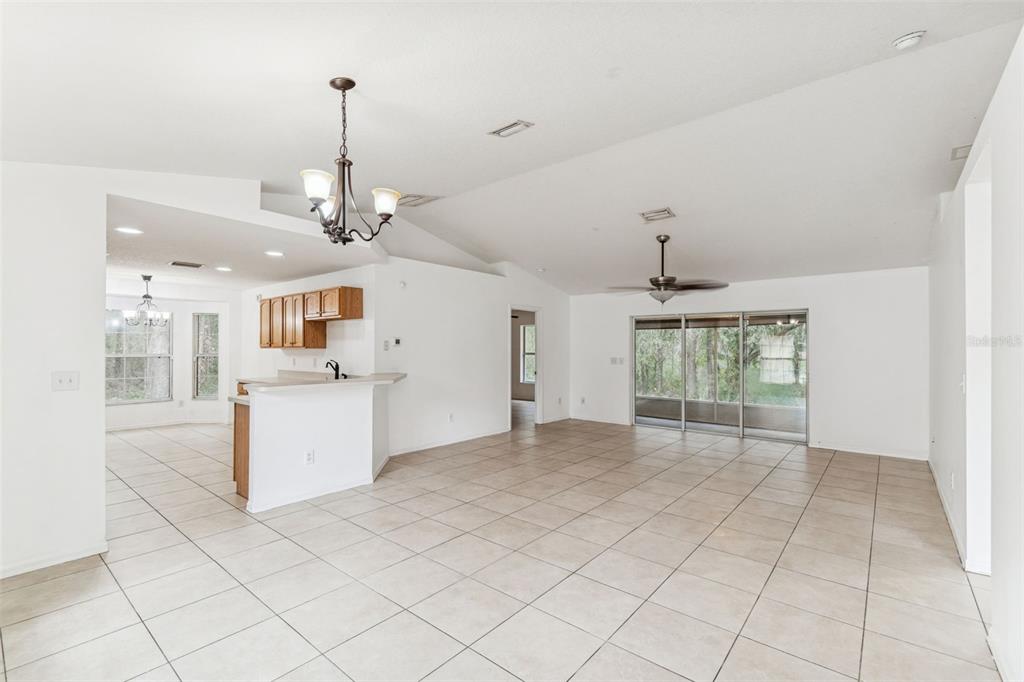 A bright, open-concept living and dining area features white walls, tile flooring, and vaulted ceilings — 14 S CHARLES AVENUE, INVERNESS, FL