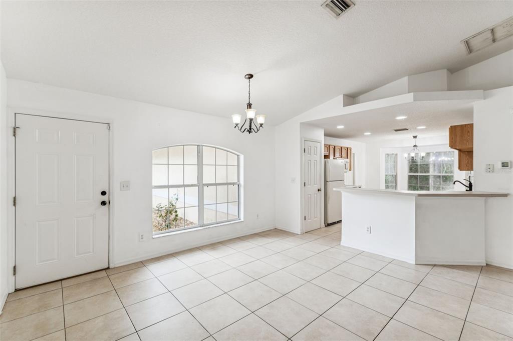 An open-concept dining area with tile flooring, a chandelier, and a breakfast bar — 14 S CHARLES AVENUE, INVERNESS, FL