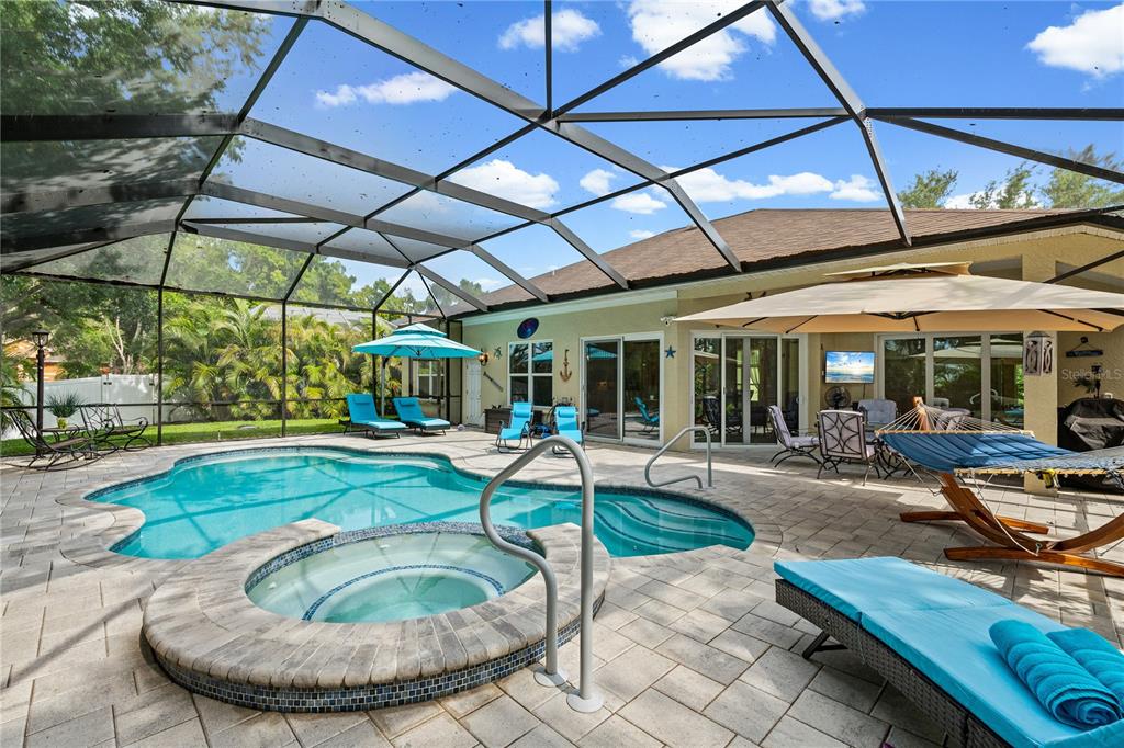 A screened-in patio features a swimming pool, a raised hot tub, and outdoor lounge furniture — 9211 12TH AVENUE NW, BRADENTON, FL