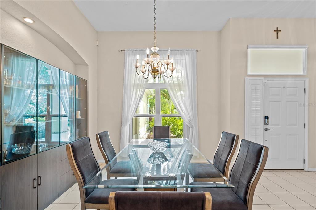 A dining room features a glass table, six upholstered chairs, a chandelier, and a display cabinet — 9211 12TH AVENUE NW, BRADENTON, FL