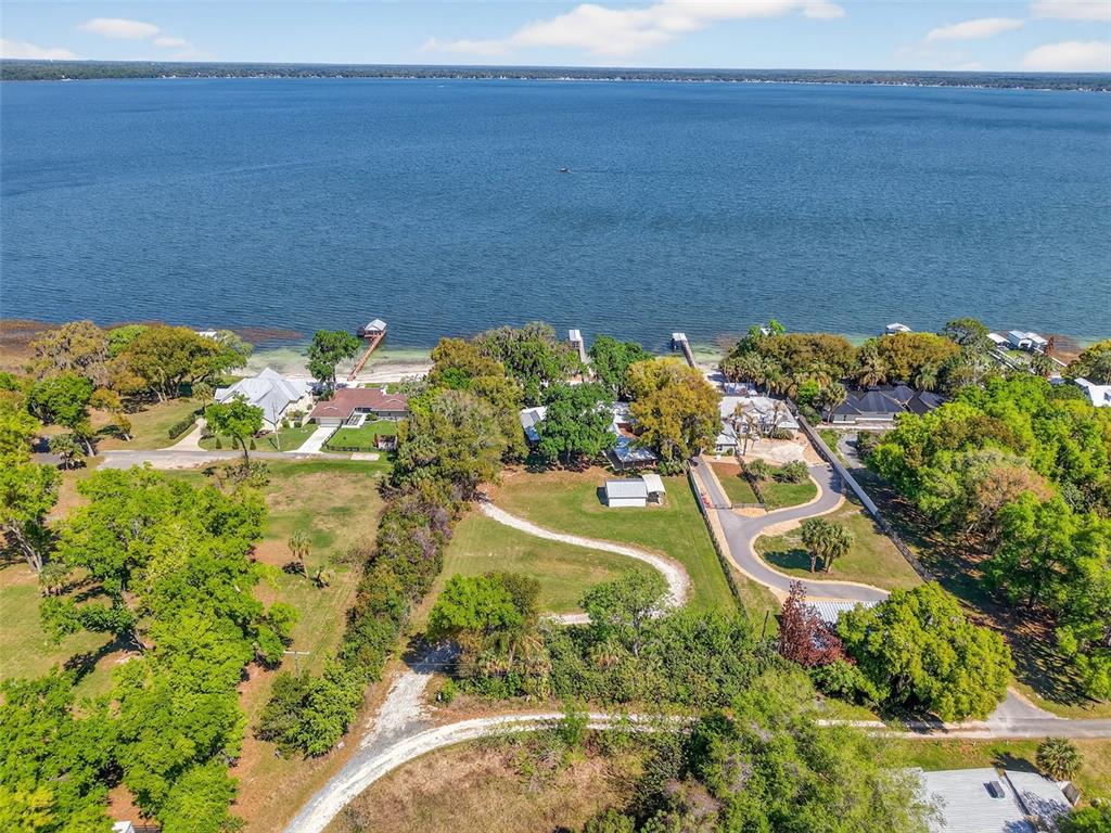 An aerial view shows several waterfront houses with private docks along a large lake — 13033 SE 158TH LANE, WEIRSDALE, FL