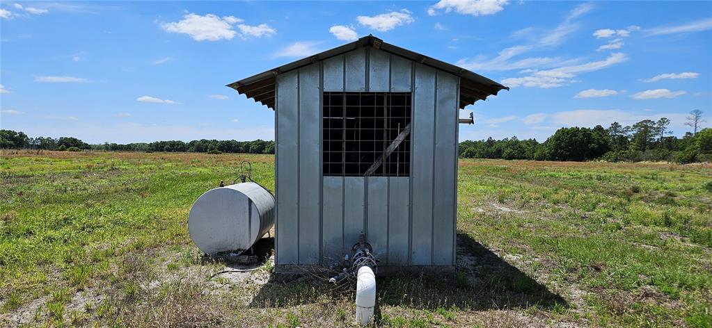 A metal shed with a fuel tank sits in a large, grassy field under a sky — MT ZION CHURF, FROSTPROOF, FL