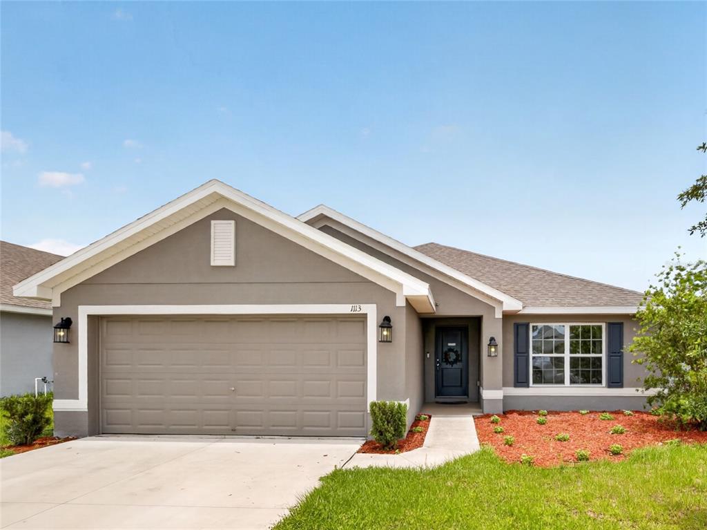 A single-story house with a gray stucco exterior, a two-car garage, and a front walkway — 1113 CITRUS LANDINGS BOULEVARD, DAVENPORT, FL
