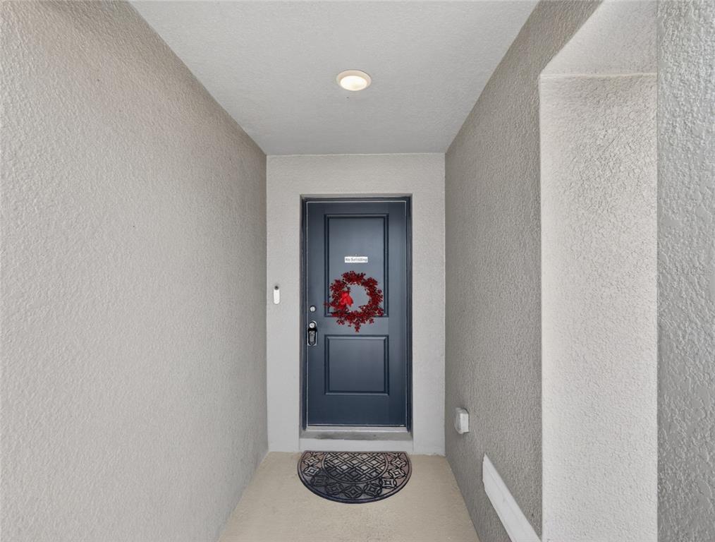 A dark blue front door with a wreath is centered in a covered entryway — 1113 CITRUS LANDINGS BOULEVARD, DAVENPORT, FL
