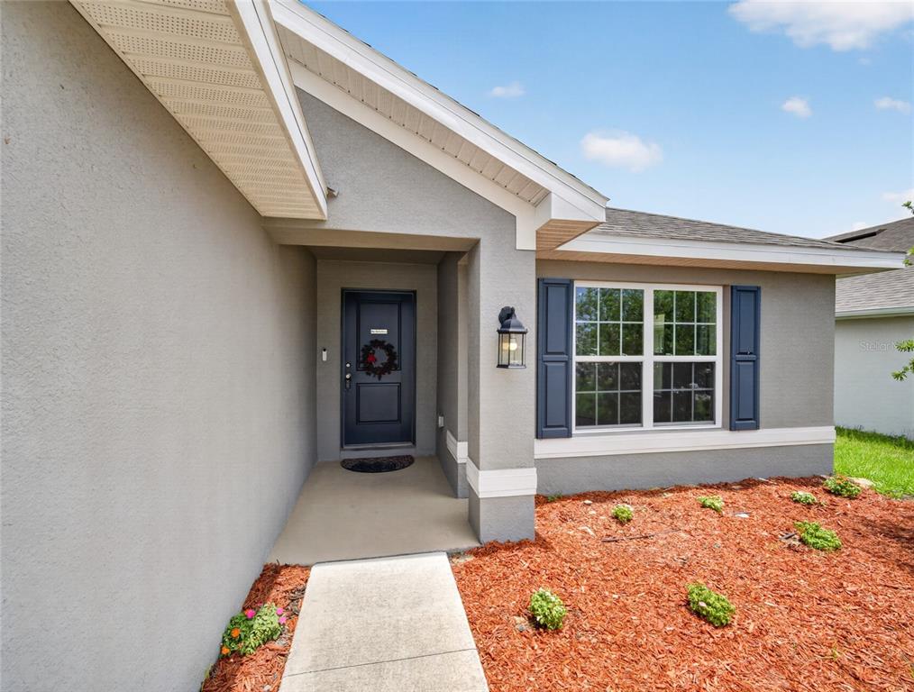 The front exterior of a gray house features a covered entryway and a single window — 1113 CITRUS LANDINGS BOULEVARD, DAVENPORT, FL